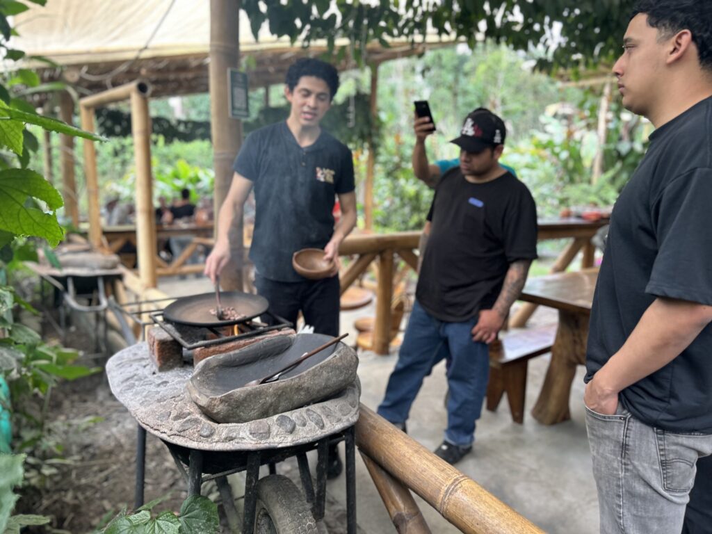 Guía mostrando el tostado artesanal del cacao junto a la piedra de moler