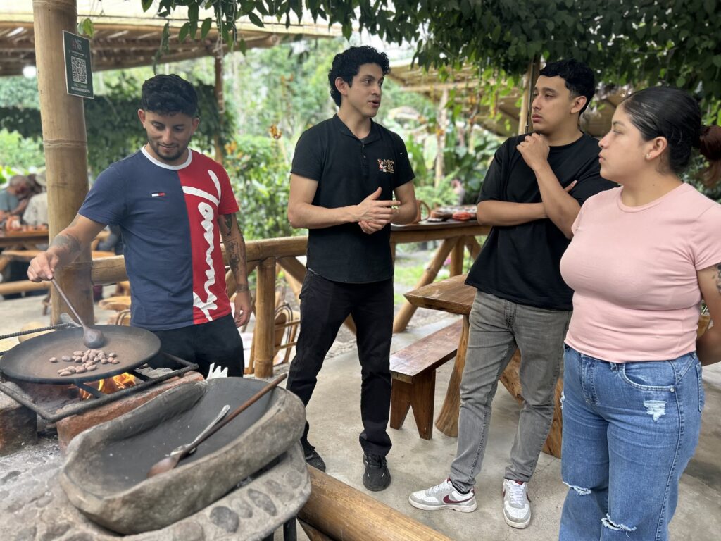 Visitante tuesta el cacao mientras el guía explica el proceso