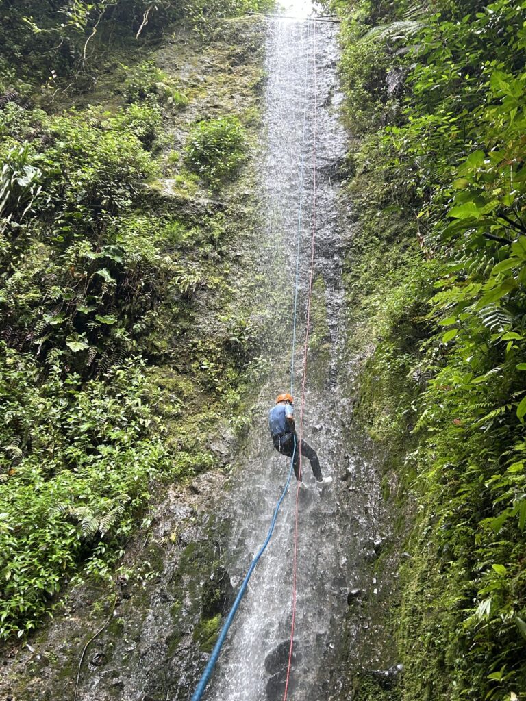 Persona descendiendo en rápel por la pared de una cascada
