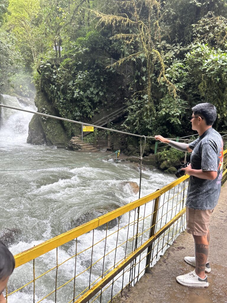 Visitantes junto a la baranda frente a la cascada y los rápidos del río de Mindo