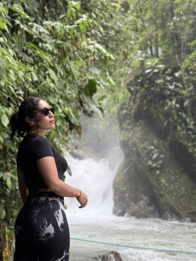 Visitante frente a una cascada entre la neblina del bosque de Mindo