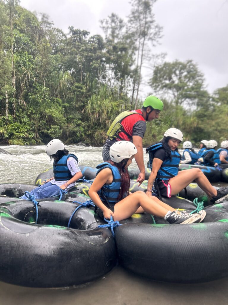 Grupo de visitantes sentado en los flotadores atados, listo para el tubing en el río