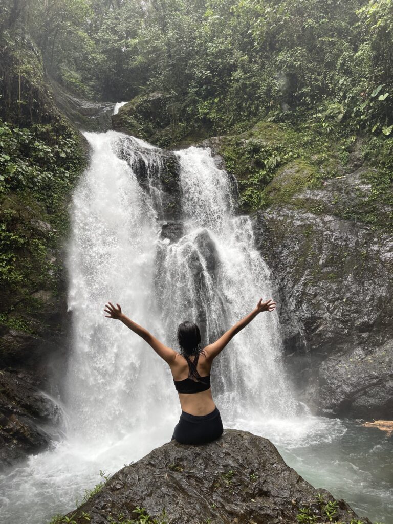 Visitante frente a la cascada, con los brazos abiertos