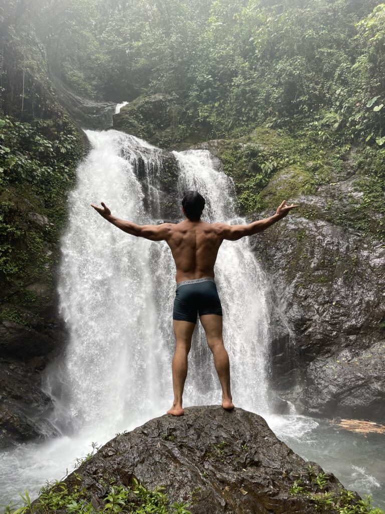 Visitante sobre la roca, frente a la caída de agua