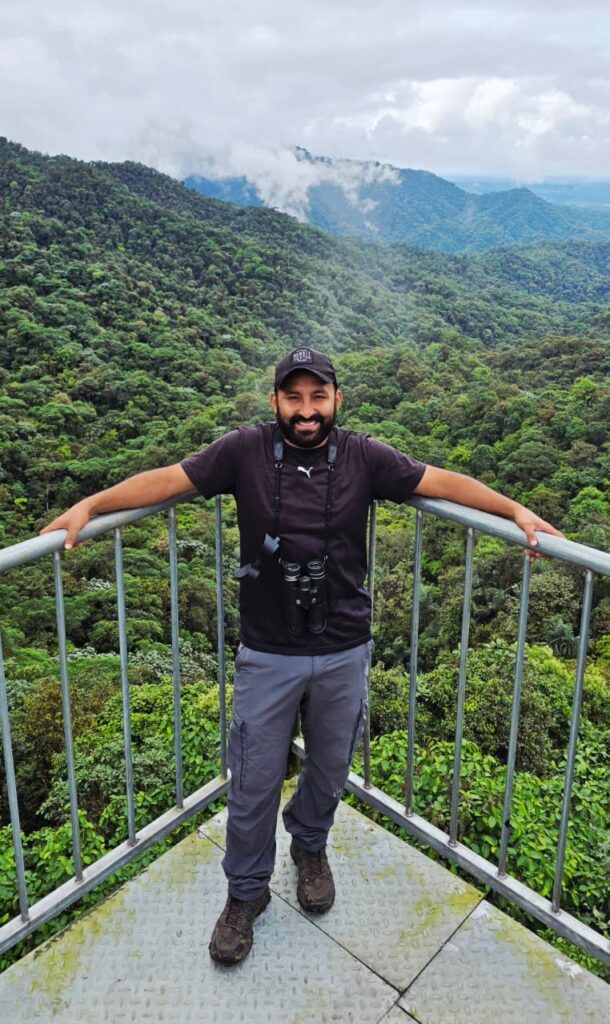 Freddy Bosmediano con binoculares en un mirador sobre el bosque nublado