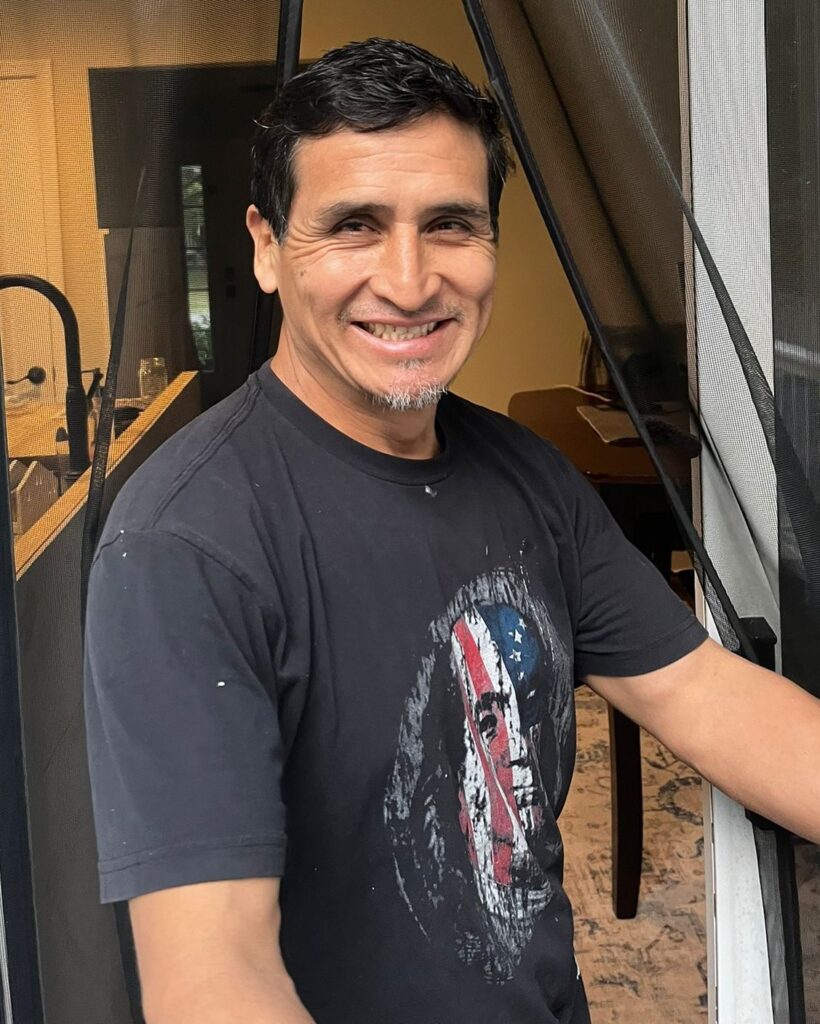 Lenin Minga, cofundador y guía de A&M Vivencial Tours, sonriendo en la puerta
