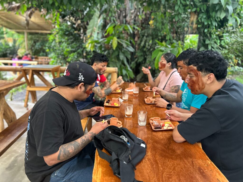Grupo de visitantes degustando chocolate en una mesa de madera
