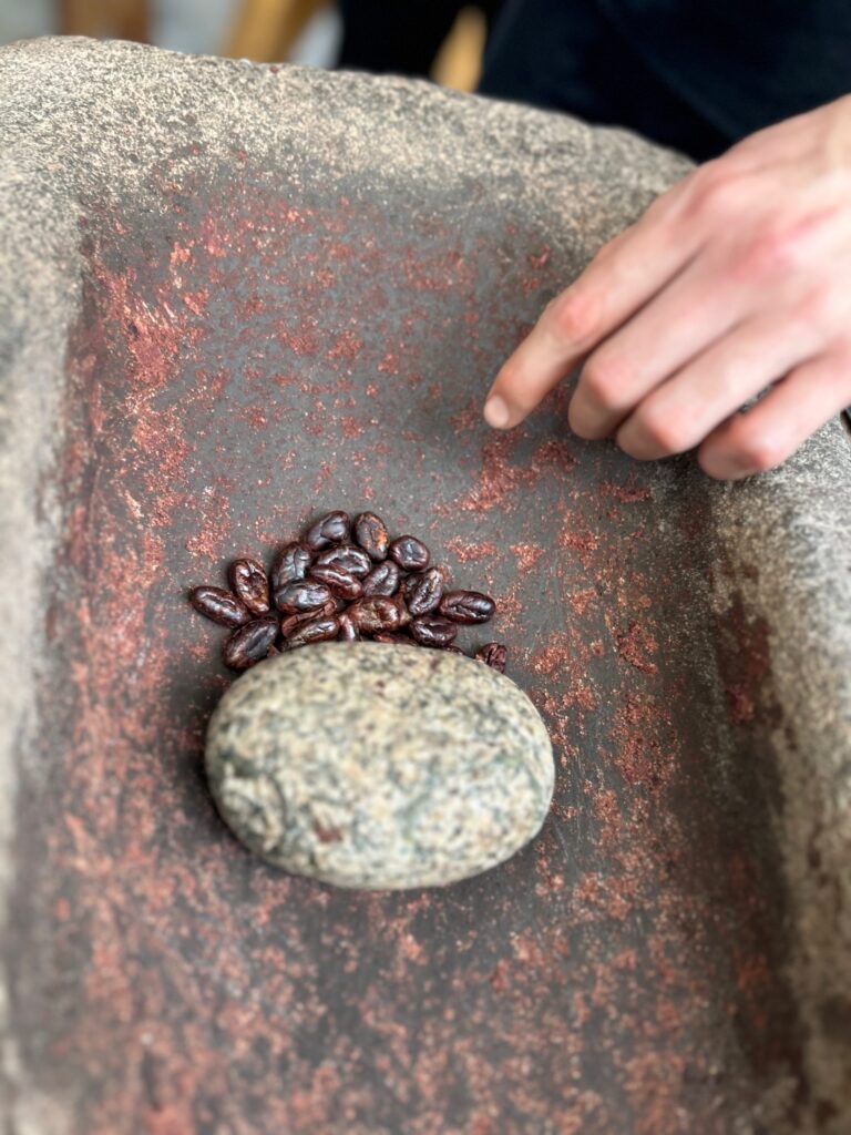 Granos de cacao tostados junto a una piedra de moler