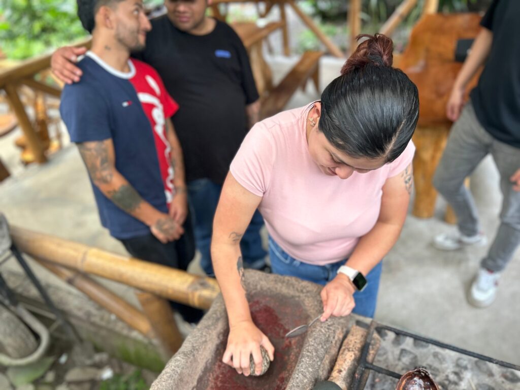 Visitante moliendo granos de cacao sobre una piedra