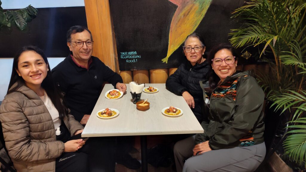 Cuatro visitantes sonriendo en una mesa con platos de degustación