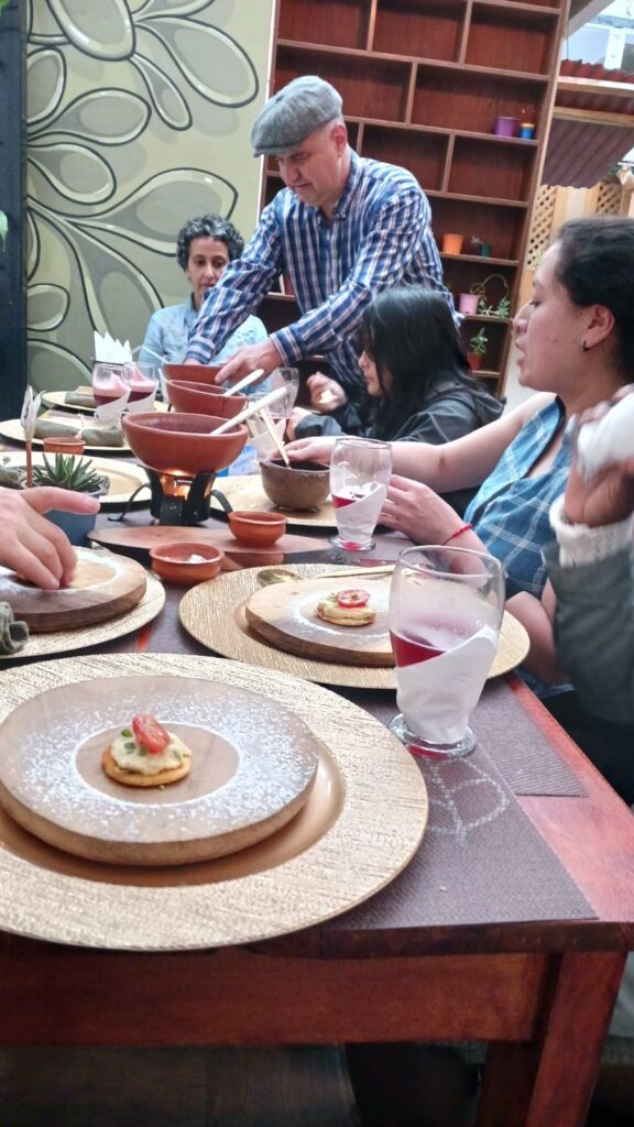 Anfitrión sirviendo platos a un grupo de visitantes en la mesa